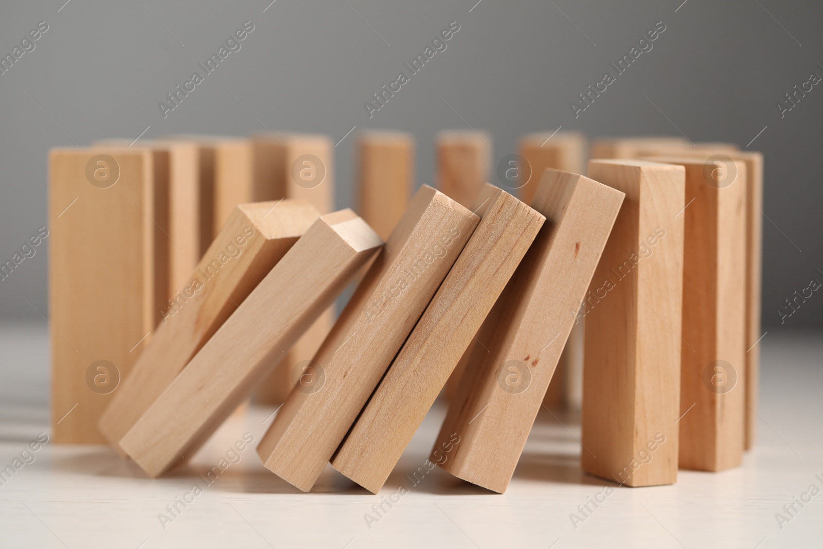 Photo of Domino effect. Wooden blocks falling on white table, closeup