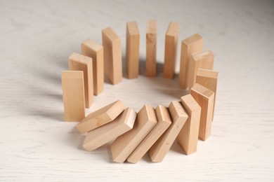 Photo of Domino effect. Wooden blocks falling on white table, closeup