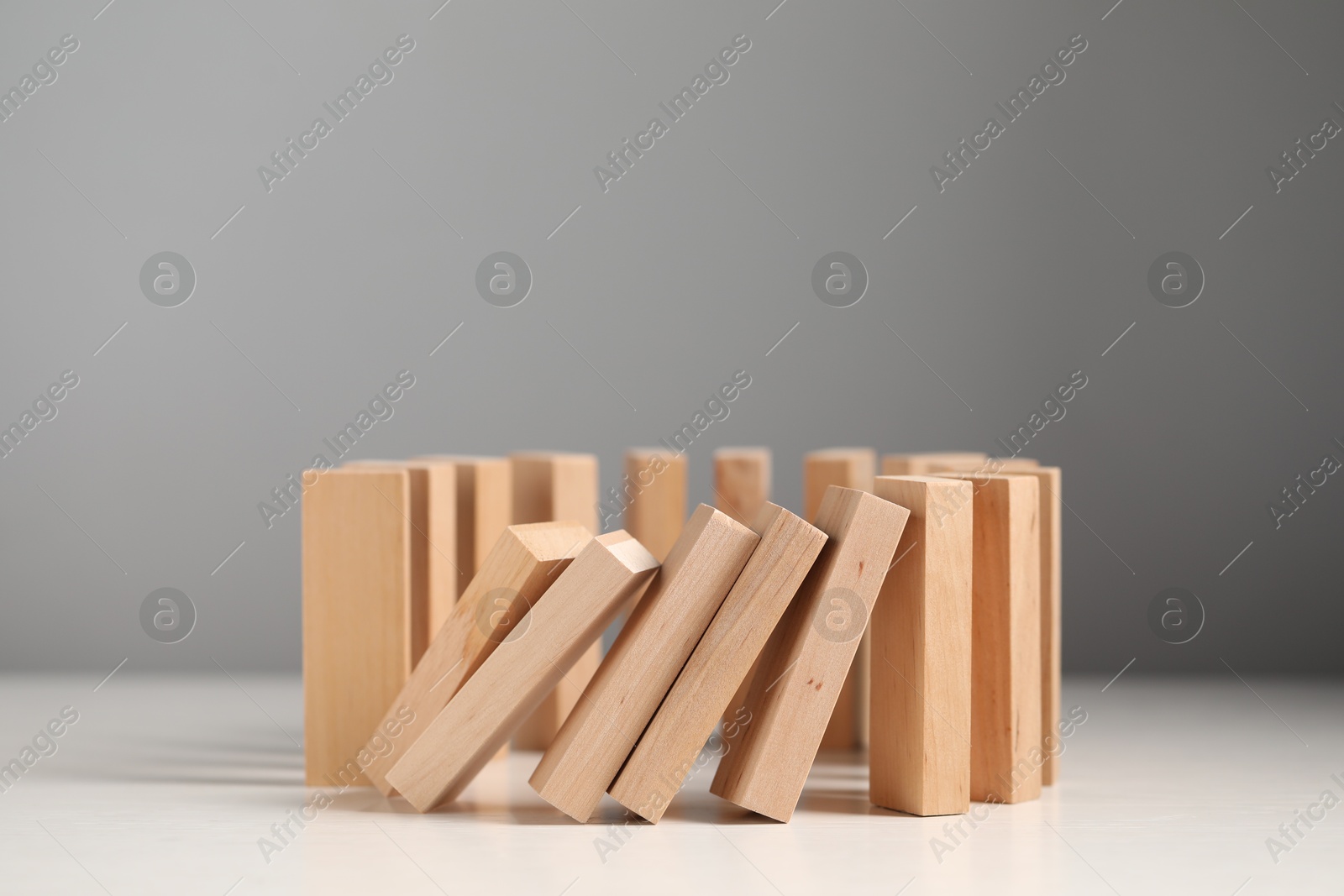 Photo of Domino effect. Wooden blocks falling on white table