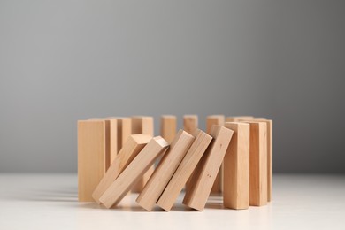 Photo of Domino effect. Wooden blocks falling on white table