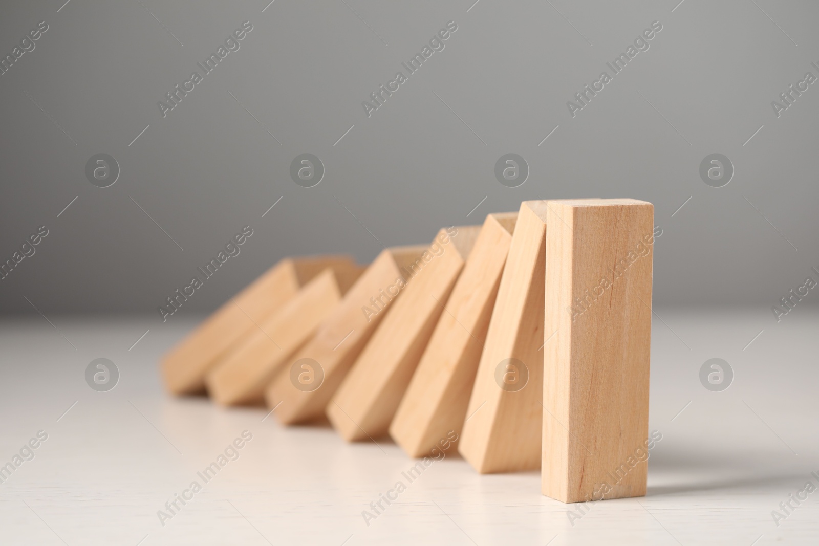 Photo of Domino effect. Wooden blocks falling on white table, closeup