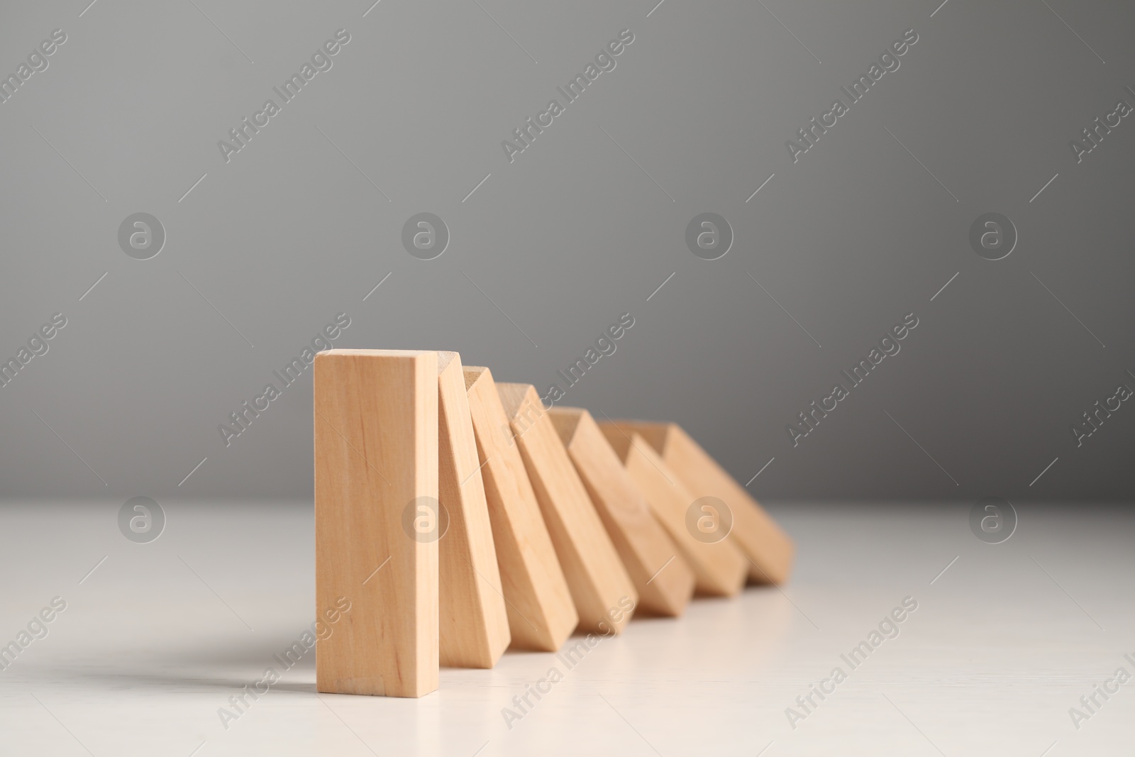 Photo of Domino effect. Wooden blocks falling on white table, closeup