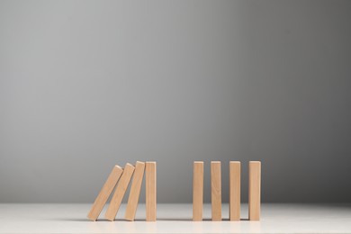 Photo of Domino effect. Wooden blocks falling on white table. Space for text