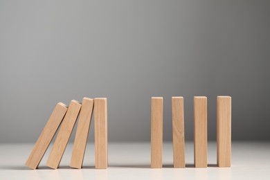 Photo of Domino effect. Wooden blocks falling on white table