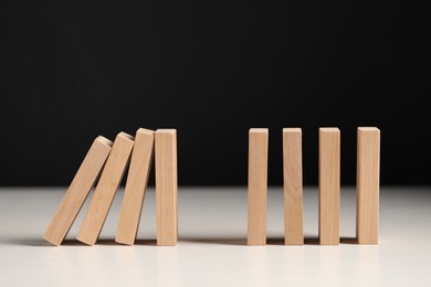 Photo of Domino effect. Wooden blocks falling on white table