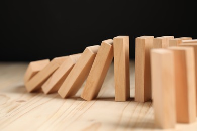 Photo of Domino effect. Blocks falling on wooden table, closeup