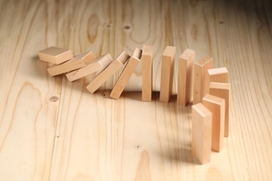 Photo of Domino effect. Blocks falling on wooden table