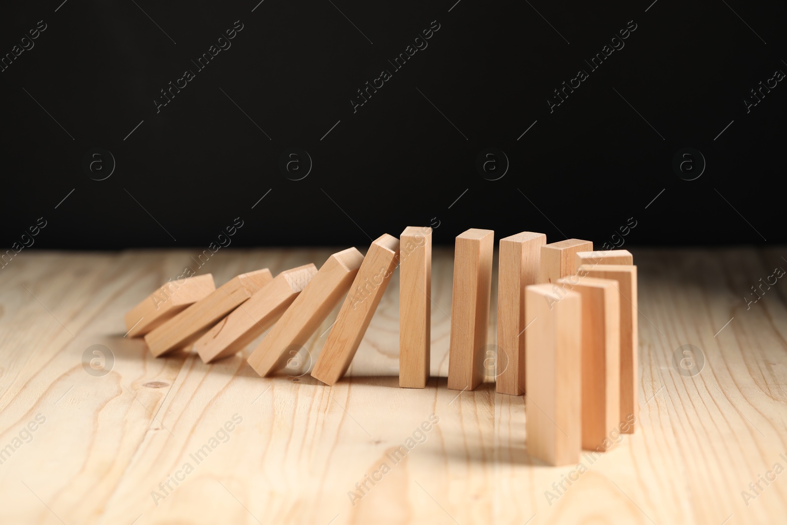 Photo of Domino effect. Blocks falling on wooden table