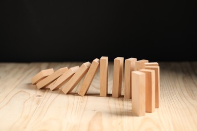 Photo of Domino effect. Blocks falling on wooden table