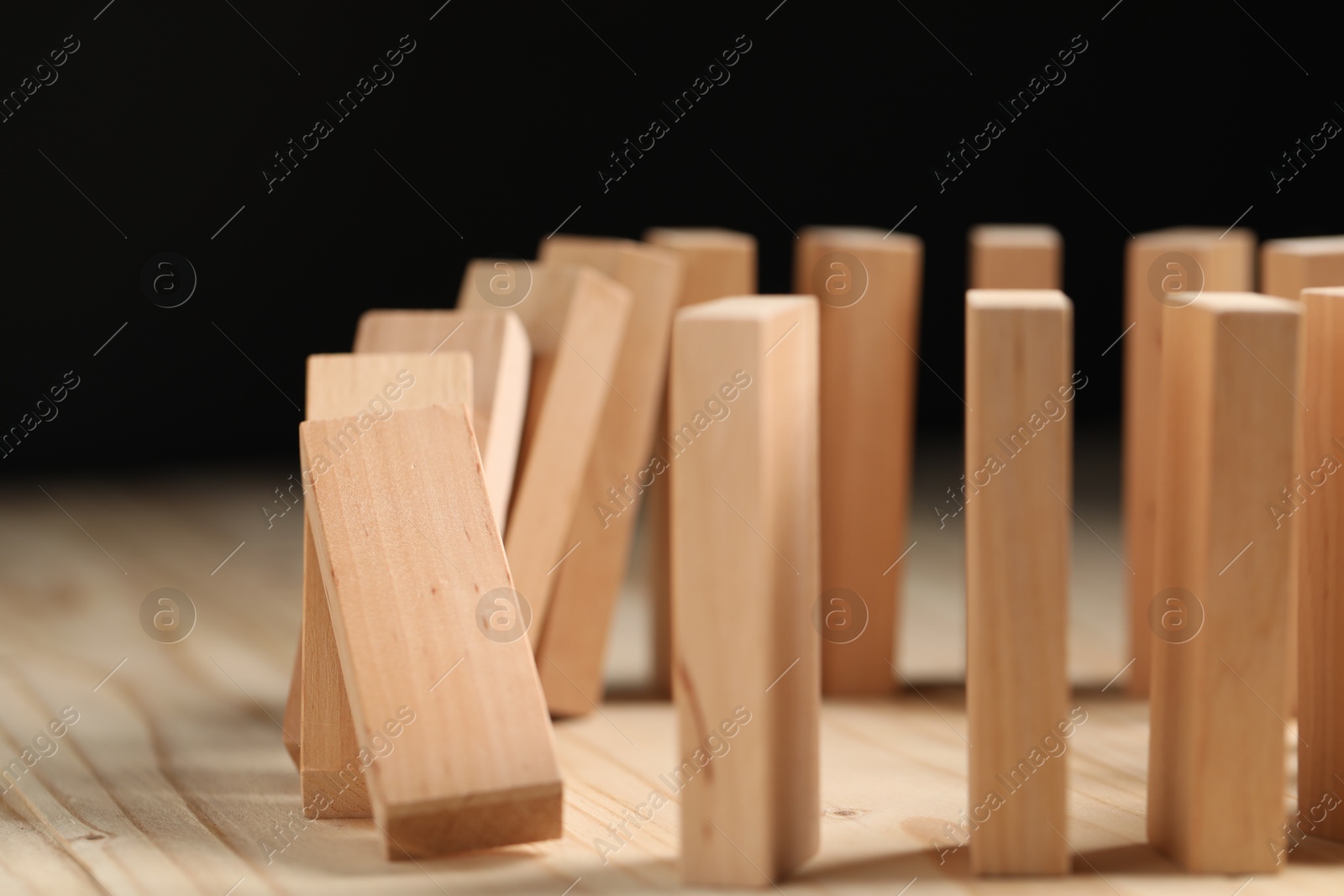 Photo of Domino effect. Blocks falling on wooden table, closeup