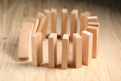 Photo of Domino effect. Blocks falling on wooden table, closeup