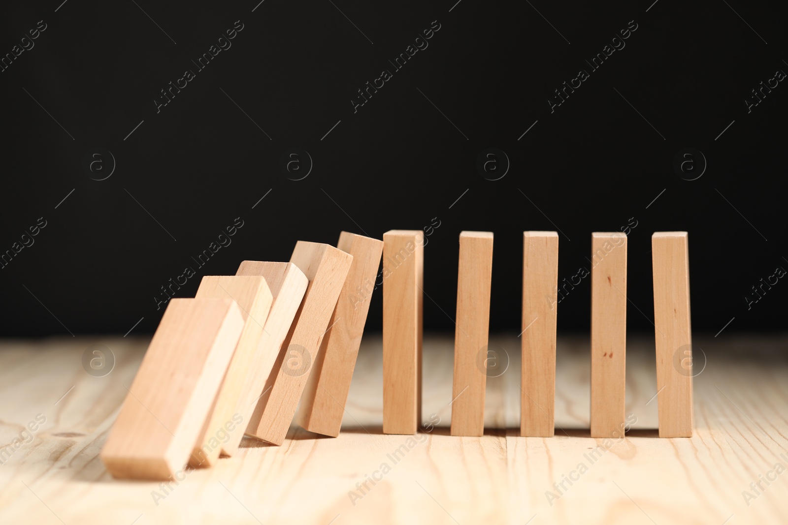 Photo of Domino effect. Blocks falling on wooden table, closeup