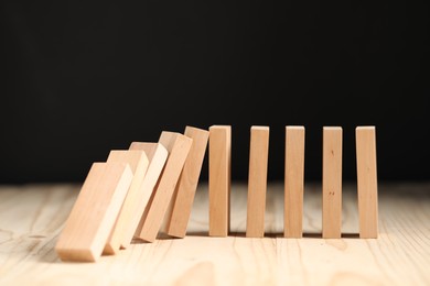 Domino effect. Blocks falling on wooden table, closeup