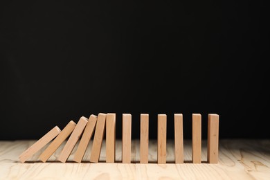 Photo of Domino effect. Blocks falling on wooden table. Space for text