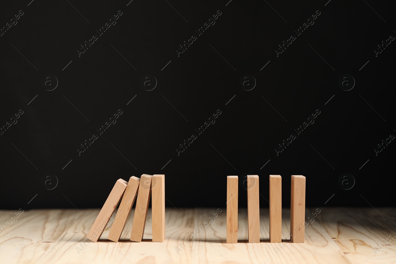 Photo of Domino effect. Blocks falling on wooden table. Space for text