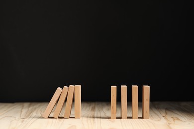 Photo of Domino effect. Blocks falling on wooden table. Space for text