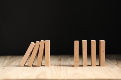 Domino effect. Blocks falling on wooden table. Space for text