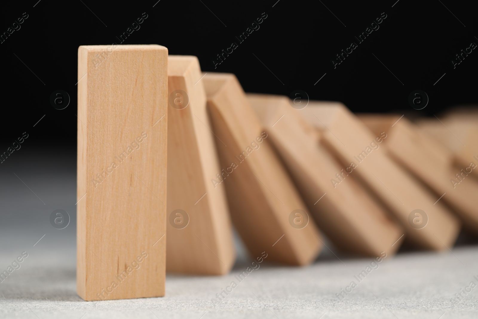 Photo of Domino effect. Wooden blocks falling on grey table, closeup