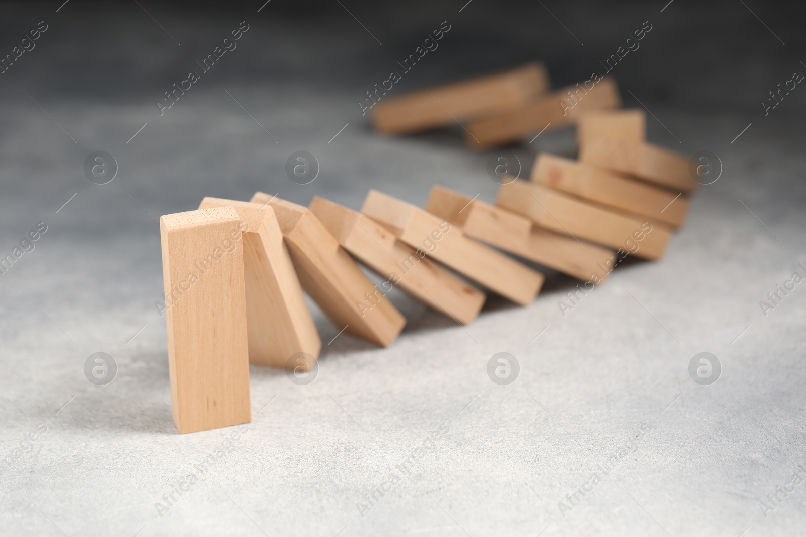 Photo of Domino effect. Wooden blocks falling on grey table, closeup