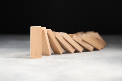 Photo of Domino effect. Wooden blocks falling on grey table, closeup