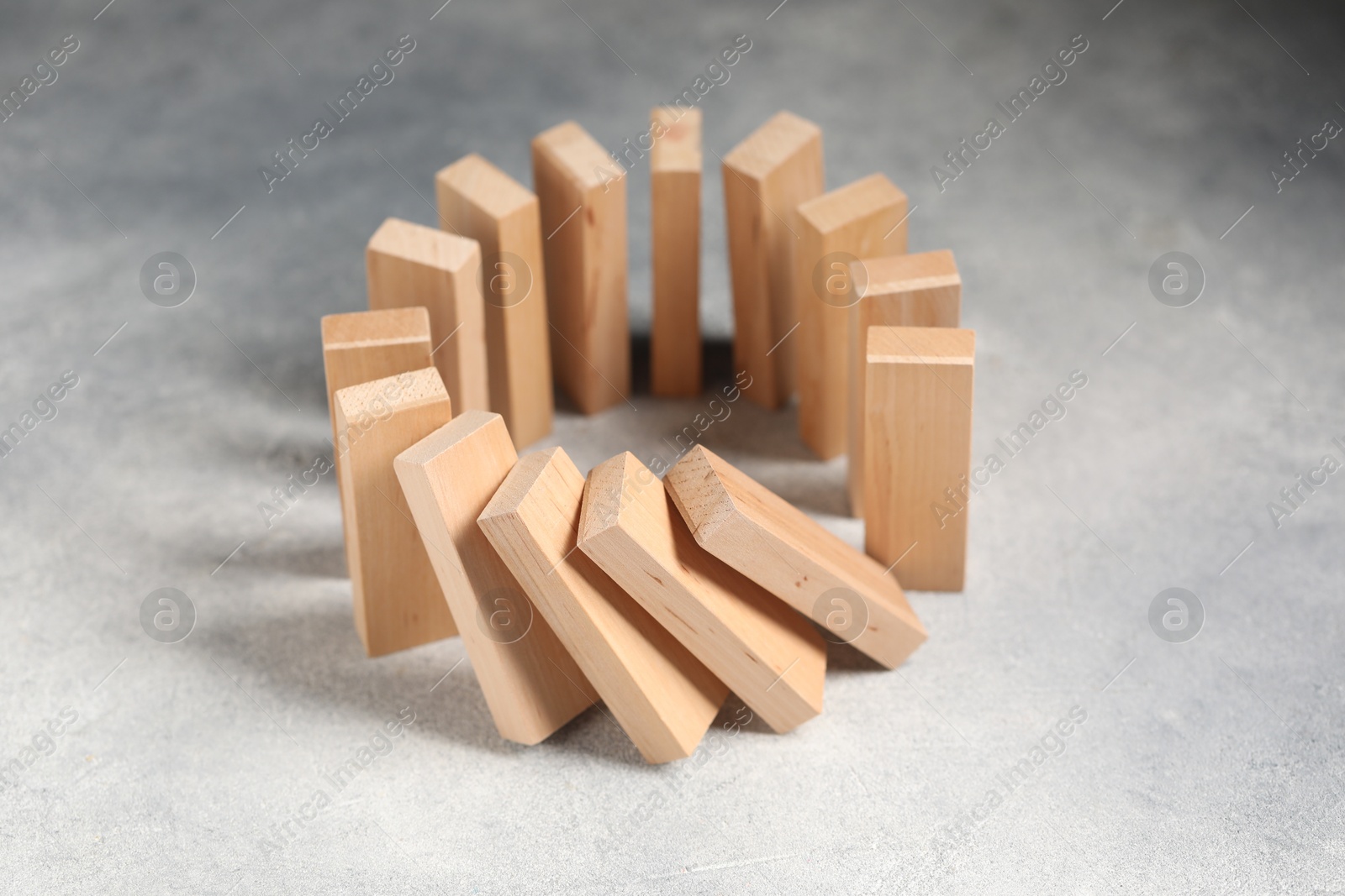 Photo of Domino effect. Wooden blocks falling on grey table, closeup