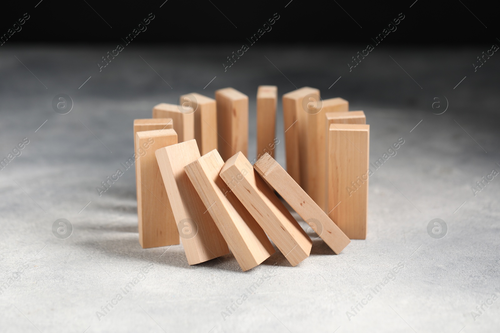 Photo of Domino effect. Wooden blocks falling on grey table, closeup