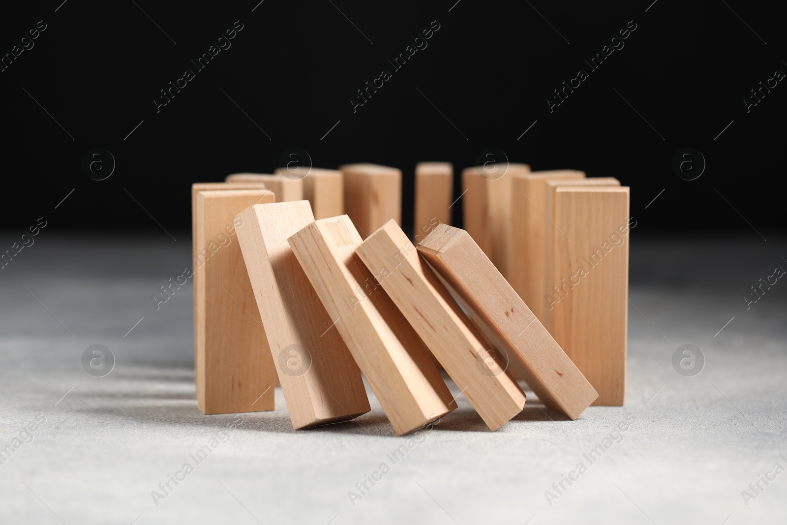 Photo of Domino effect. Wooden blocks falling on grey table, closeup