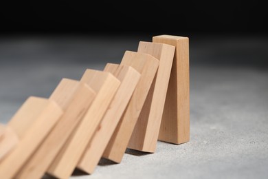 Photo of Domino effect. Wooden blocks falling on grey table, closeup