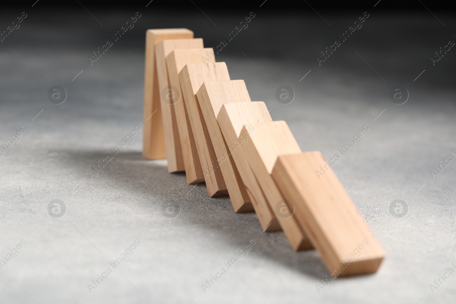 Photo of Domino effect. Wooden blocks falling on grey table, closeup