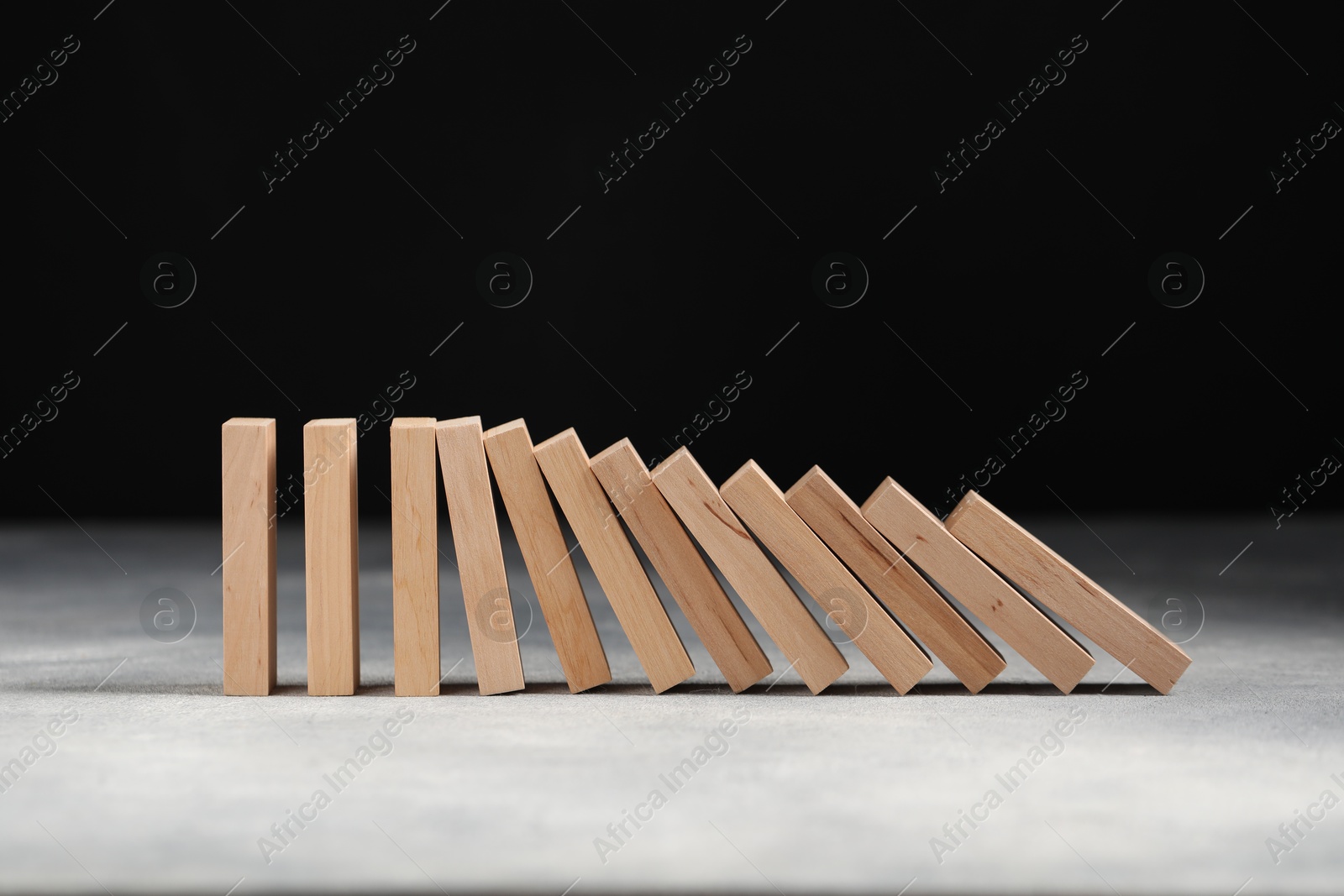 Photo of Domino effect. Wooden blocks falling on grey table