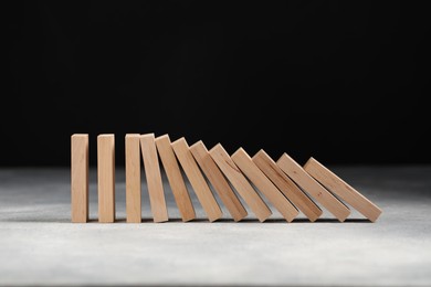 Photo of Domino effect. Wooden blocks falling on grey table