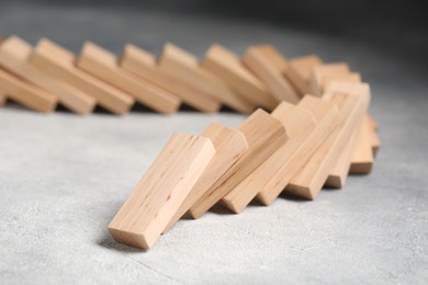 Photo of Domino effect. Wooden blocks falling on grey table, closeup