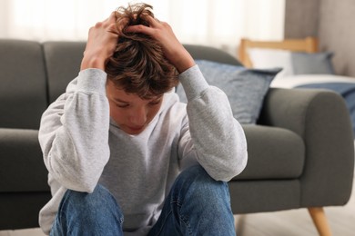 Photo of Loneliness concept. Sad teenage boy on floor at home