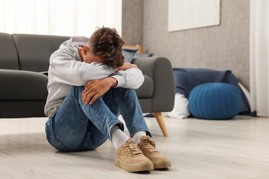 Loneliness concept. Sad teenage boy on floor at home