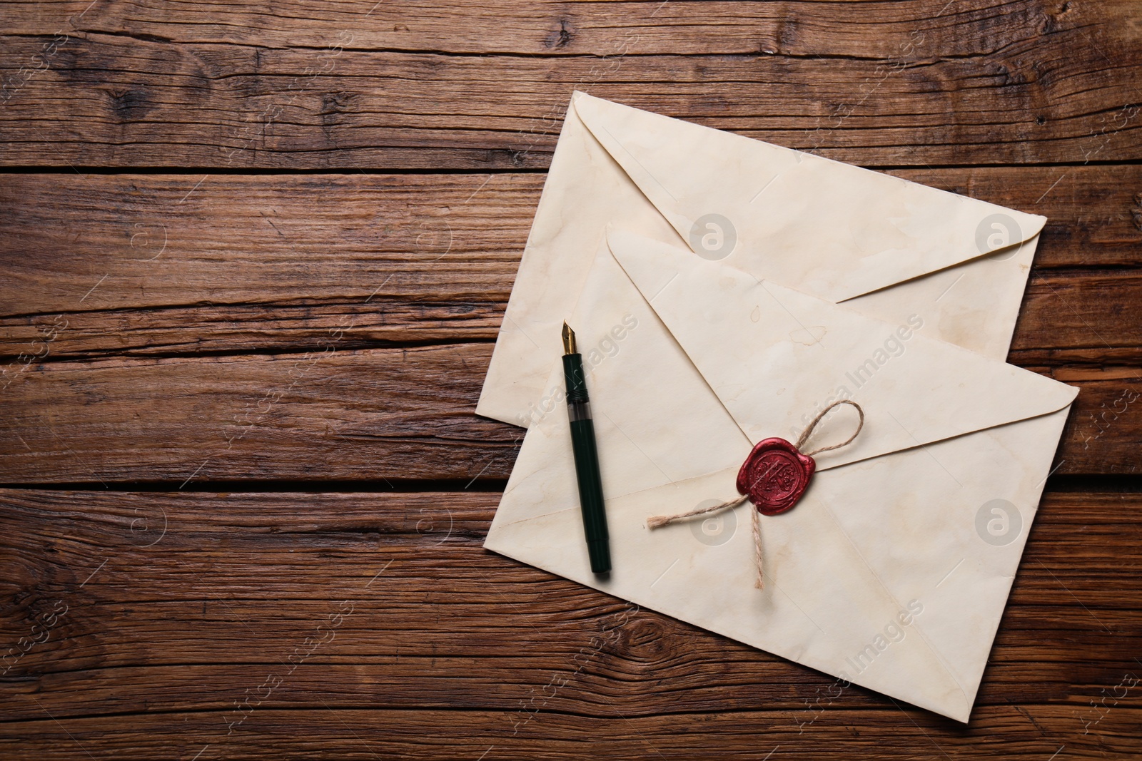 Photo of Old letter envelopes and pen on wooden table, top view. Space for text