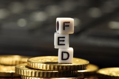 Photo of Cubes with letters Fed (Federal Reserve System) and coins on table, closeup