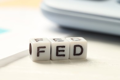 Photo of Cubes with letters Fed (Federal Reserve System) on white table, closeup