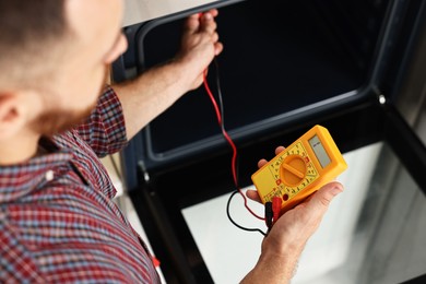 Repairman testing oven element with multimeter, closeup