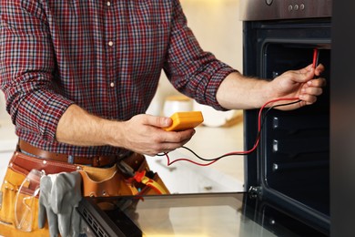 Photo of Repairman testing oven element with multimeter, closeup