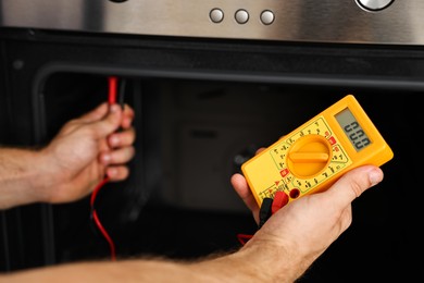 Repairman testing oven element with multimeter, closeup