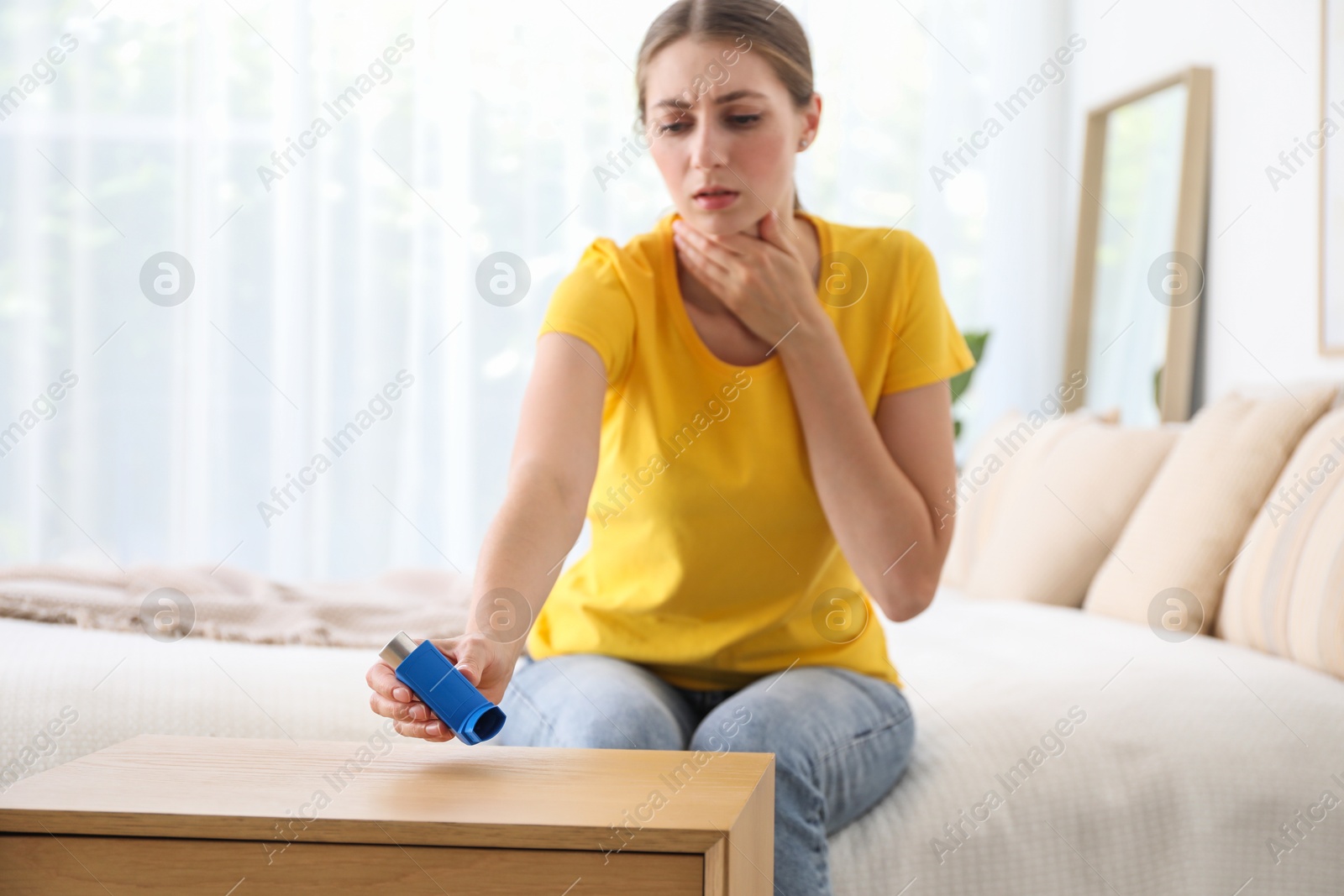 Photo of Young woman using asthma inhaler at home, selective focus