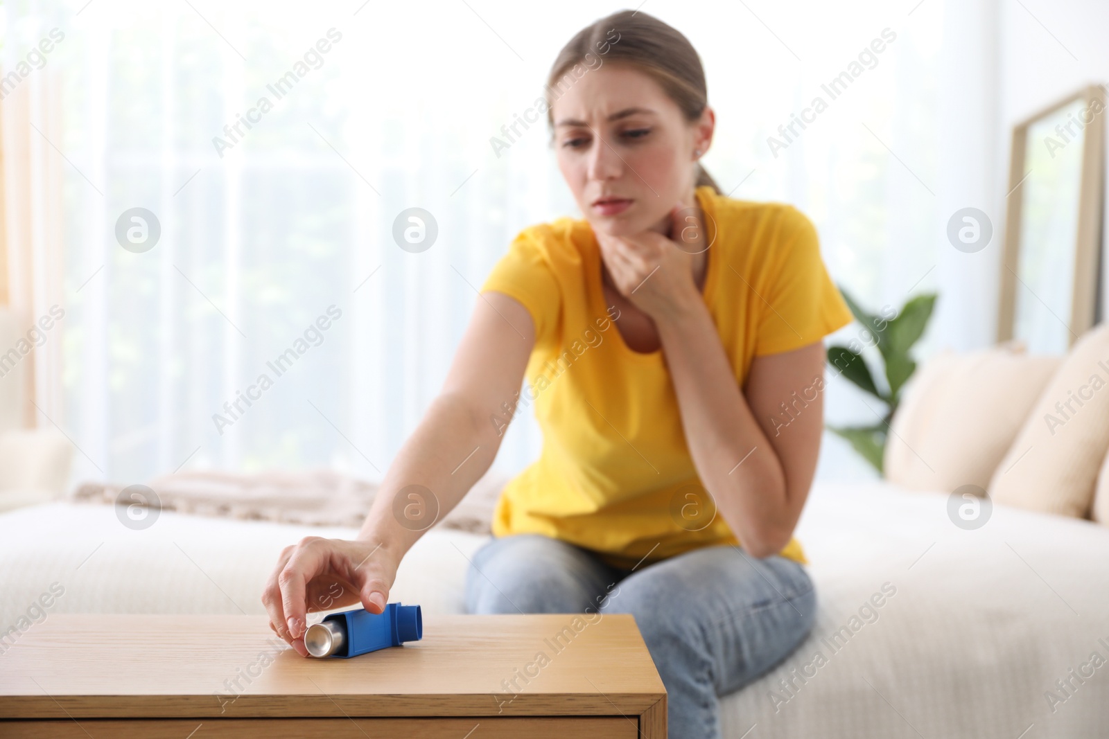 Photo of Young woman using asthma inhaler at home, selective focus