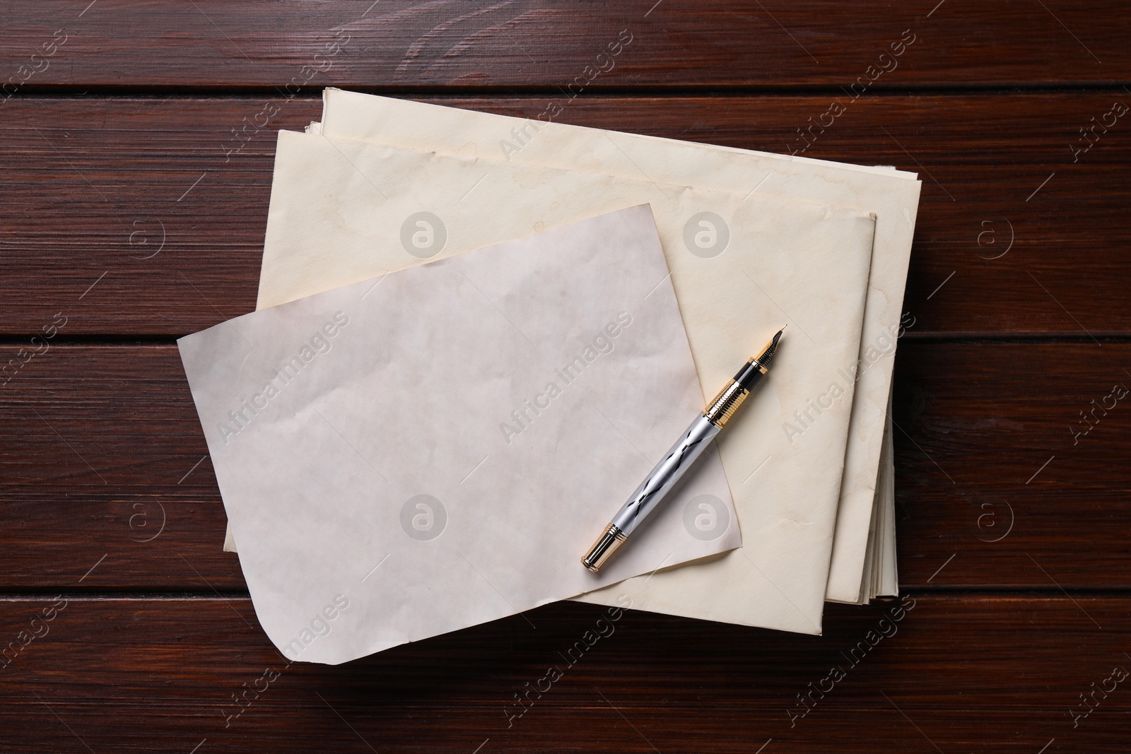 Photo of Old letter, fountain pen and envelopes on wooden table, top view