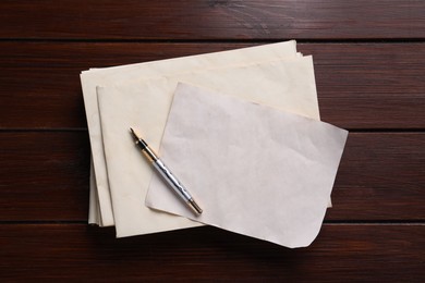 Photo of Old letter, fountain pen and envelopes on wooden table, top view