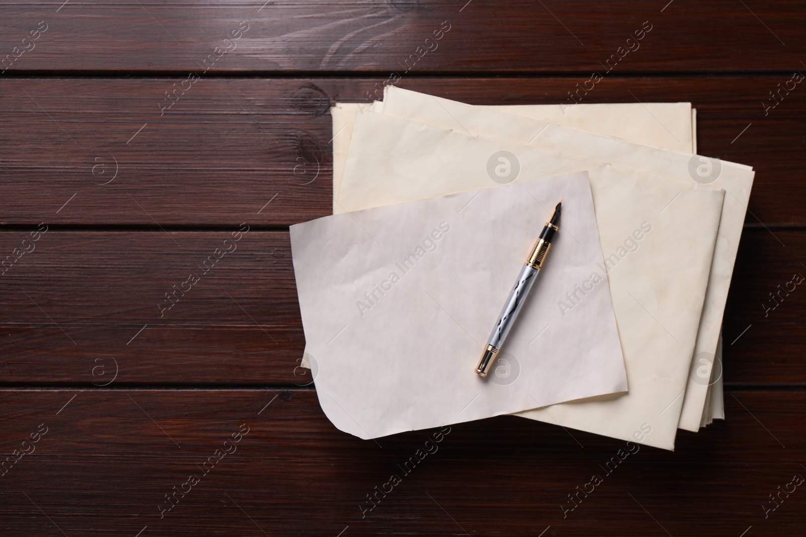 Photo of Old letter, fountain pen and envelopes on wooden table, top view. Space for text