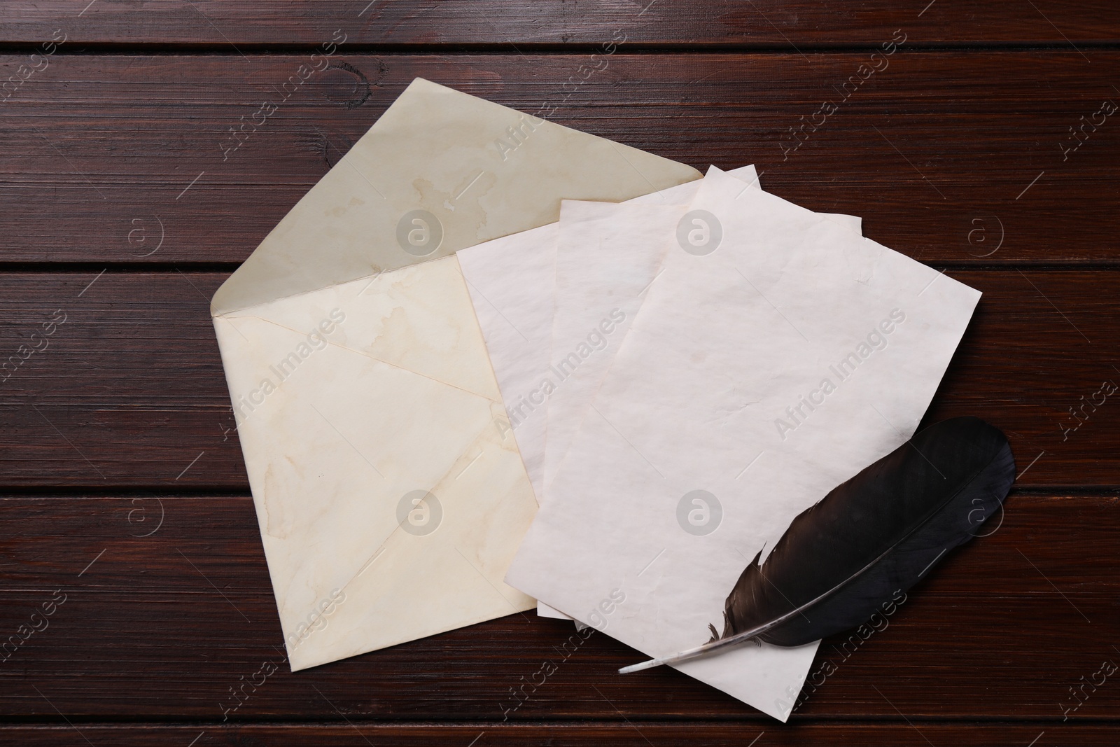 Photo of Old letters, envelope and feather on wooden table, top view