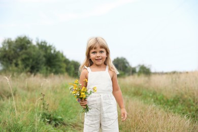 Photo of Cute little girl with flowers at meadow. Child enjoying beautiful nature