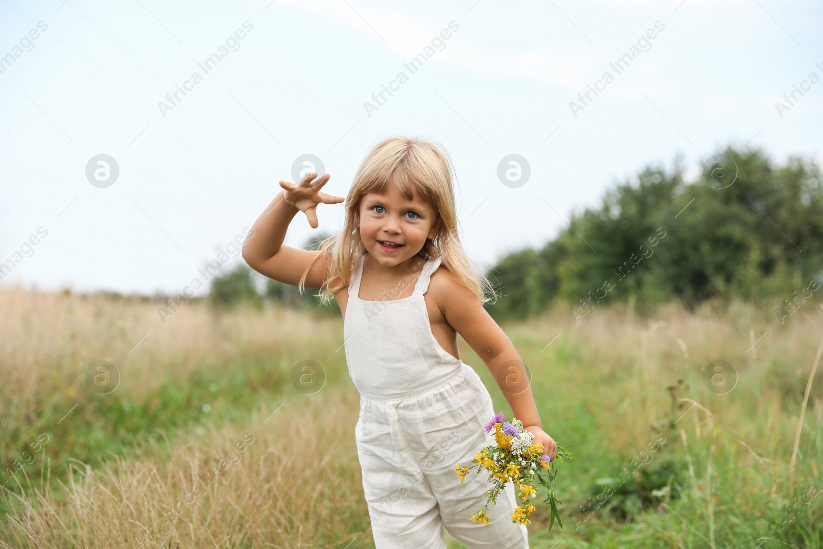 Photo of Cute little girl with flowers at meadow. Child enjoying beautiful nature