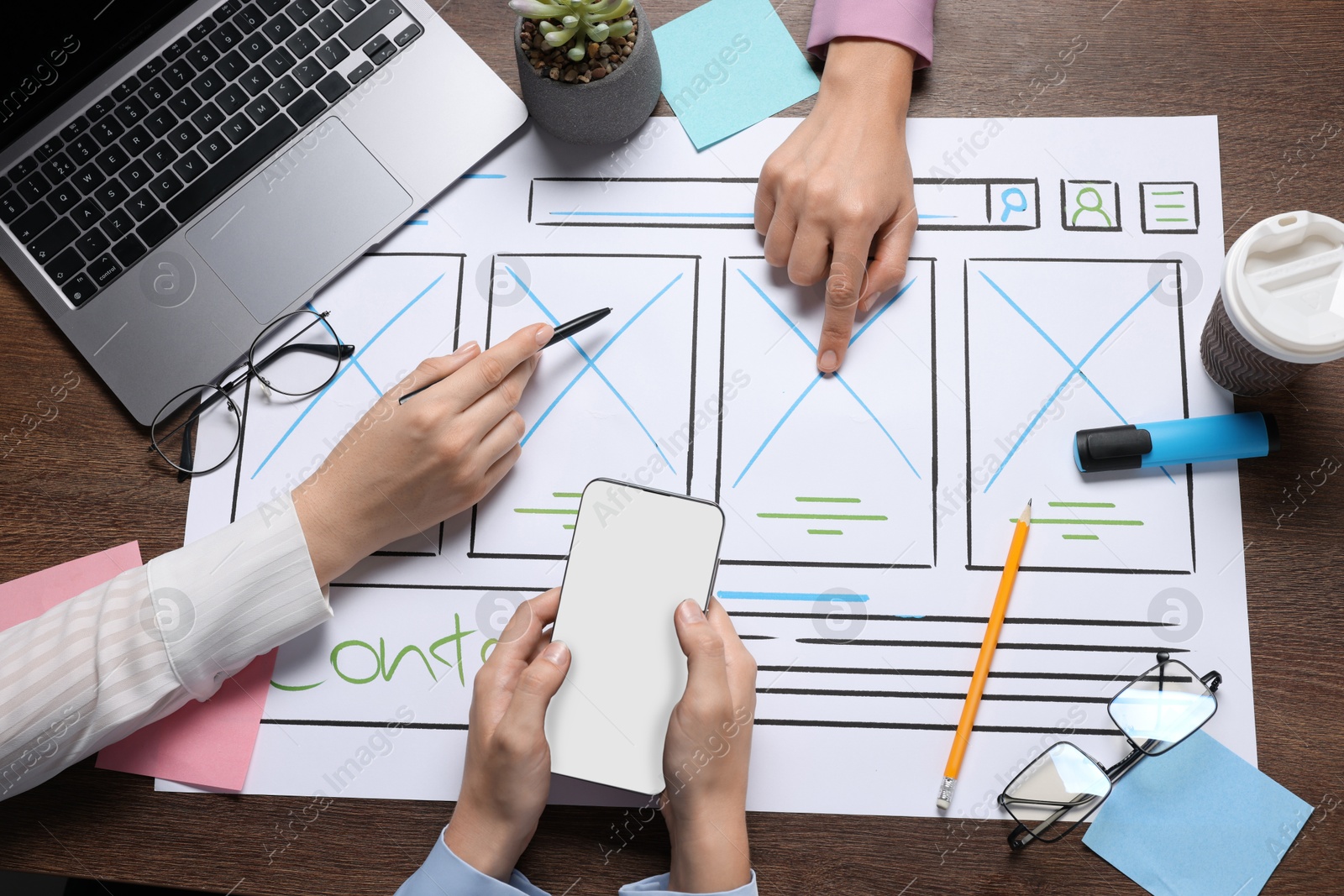 Photo of Developing UI design. Designers creating website wireframe on paper at wooden table, top view