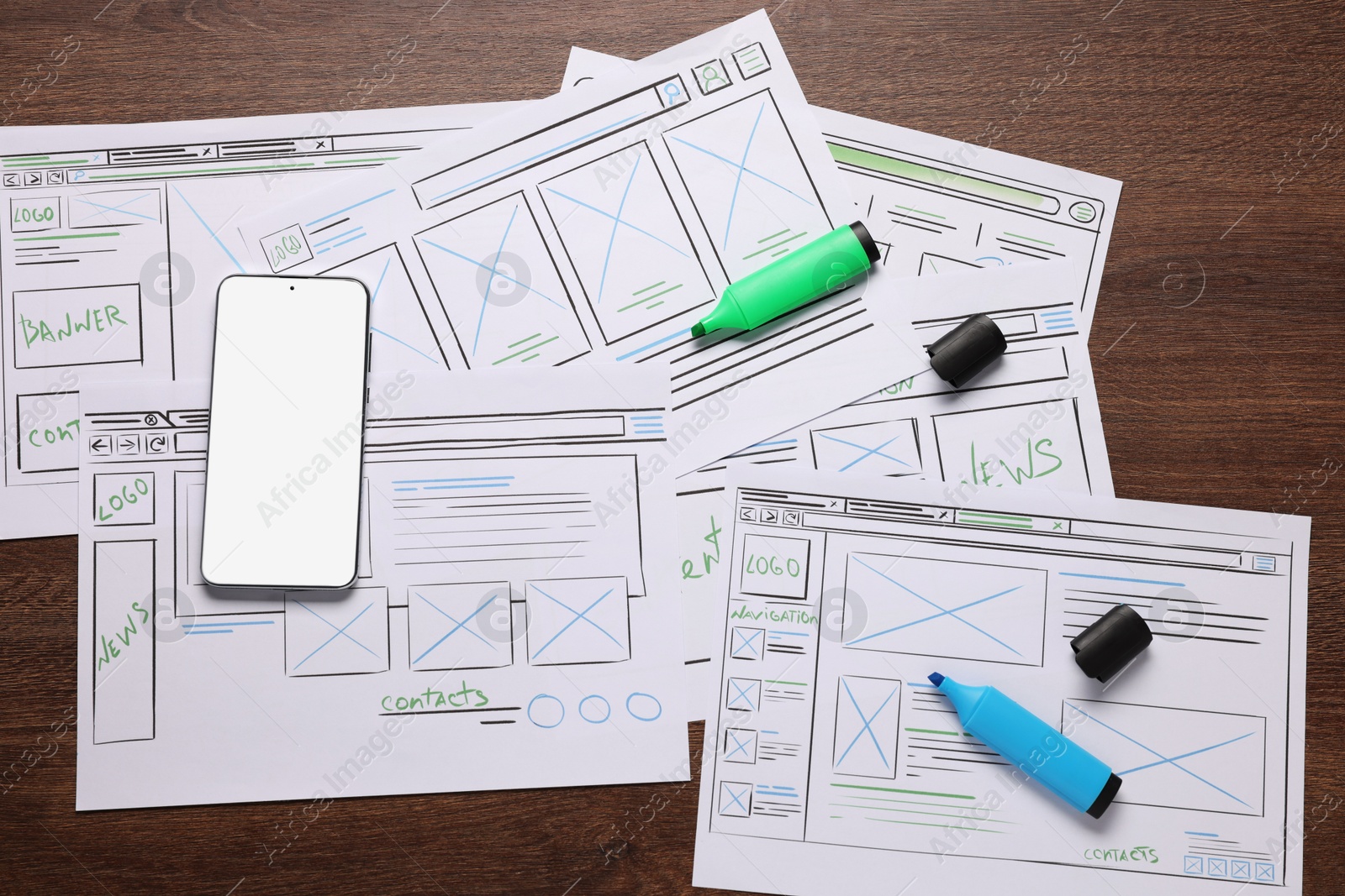 Photo of Developing UI design. Sketches of website wireframes, smartphone and felt pens on wooden table, top view